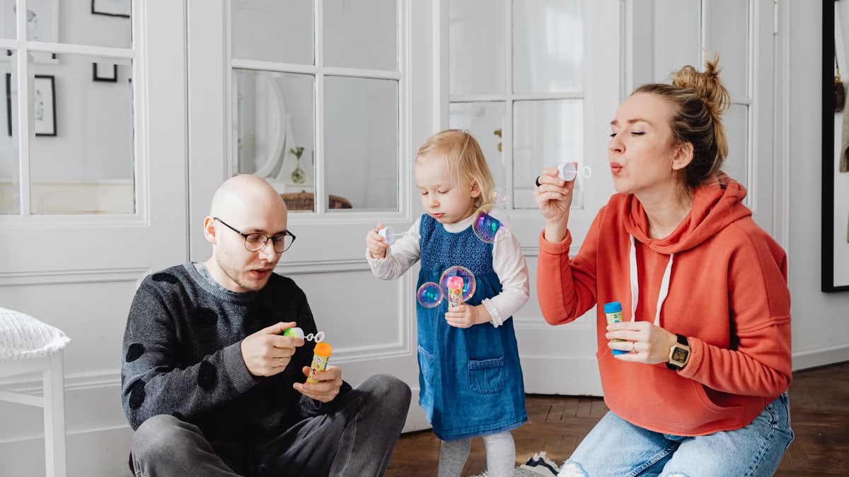 Family enjoying quality time blowing bubbles indoors, capturing joyful moments.