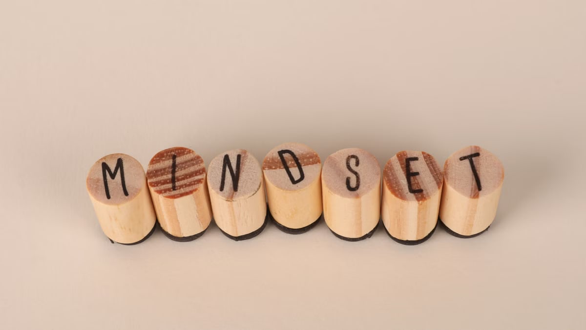 Wooden letter stamps spelling 'Mindset' on a simple beige background, conveying focus and positive thinking.